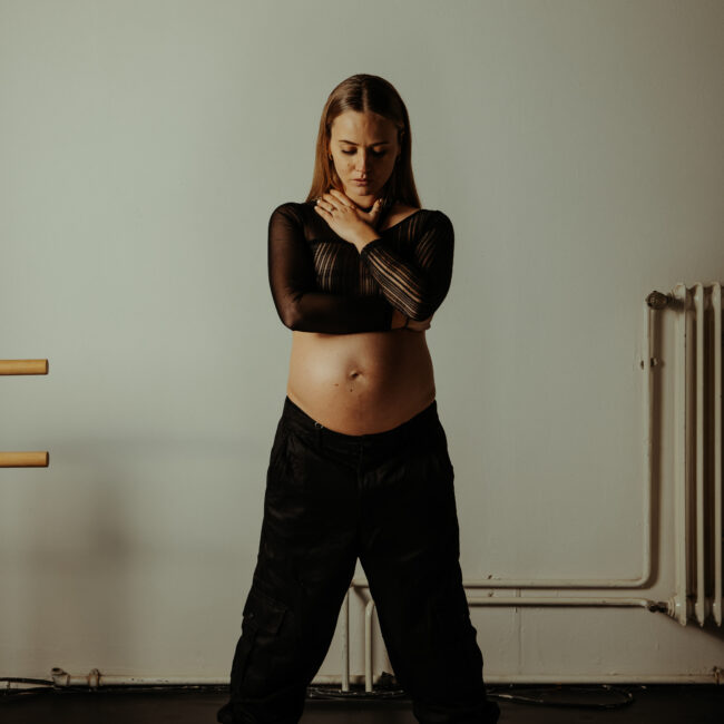 hier ist der maternity fotografie service zu sehen. Die schwangere Frau trägt schwarze kleidung und der Bauch ist frei.