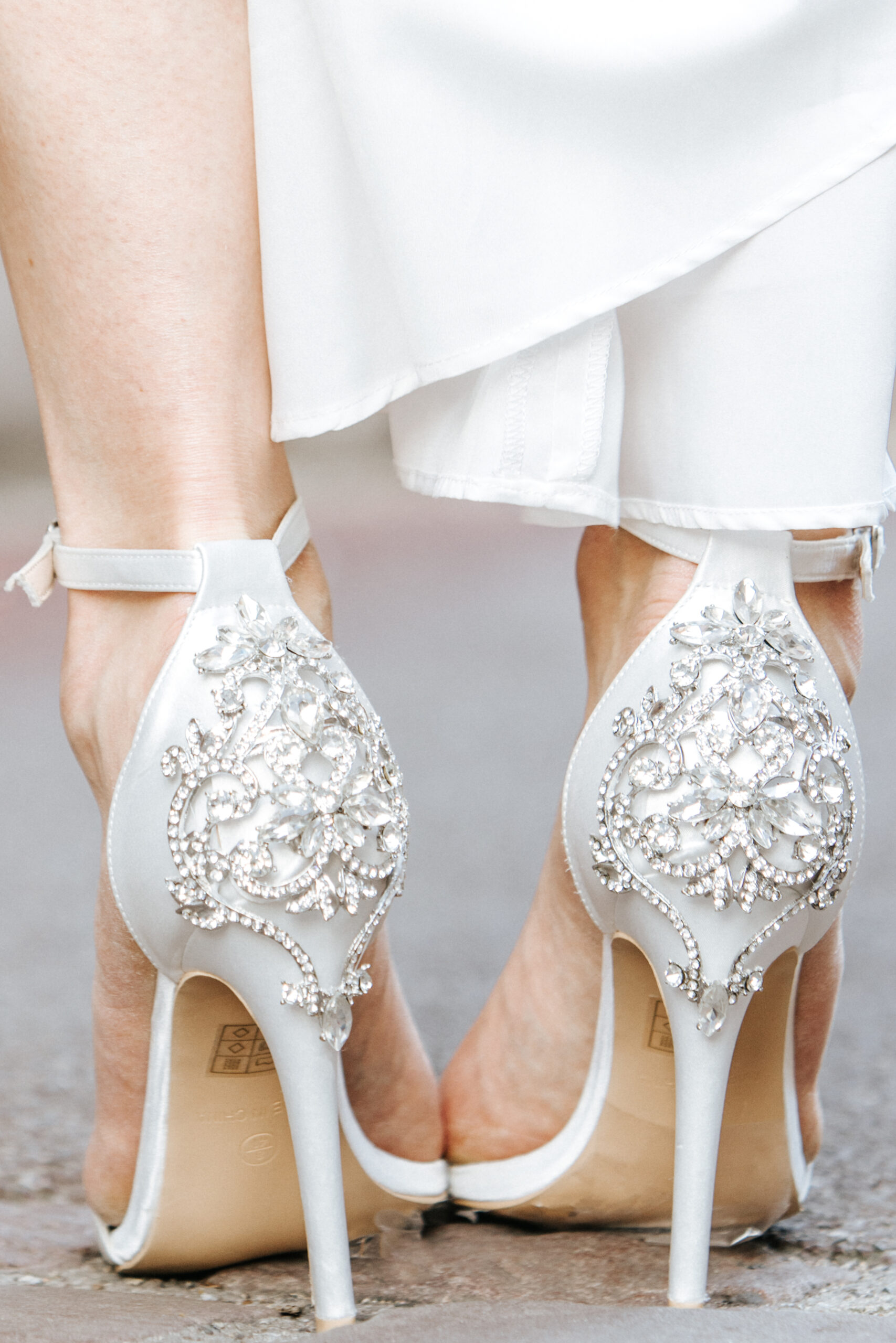 Afterweddingshooting with Bridedetails. Shoes, Earrings, Lovely Bridaldress. Detailaufnahme der High Heels und Beine der Braut in den Straßen von Mallorca. Dabei weht das Brautkleid leicht über die Knöchel der Braut.