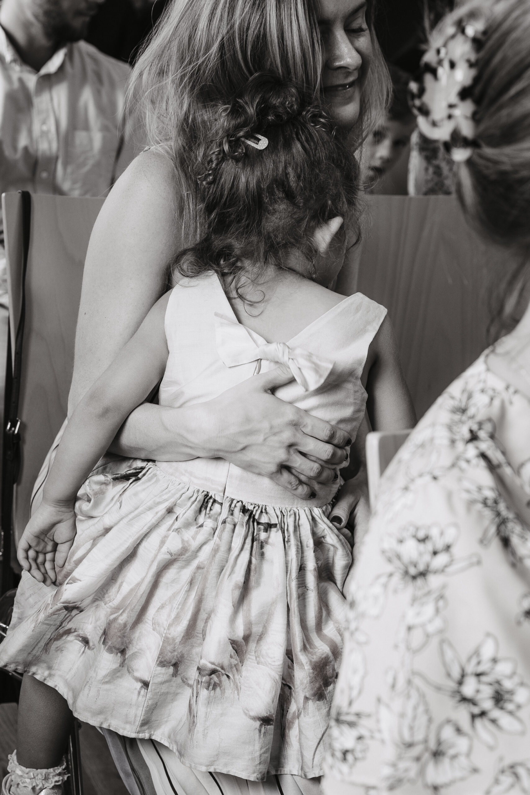 Ein Hochzeitsgast kuschelt mit Ihrer Tochter und umarmt sie liebevoll während der Trauung
