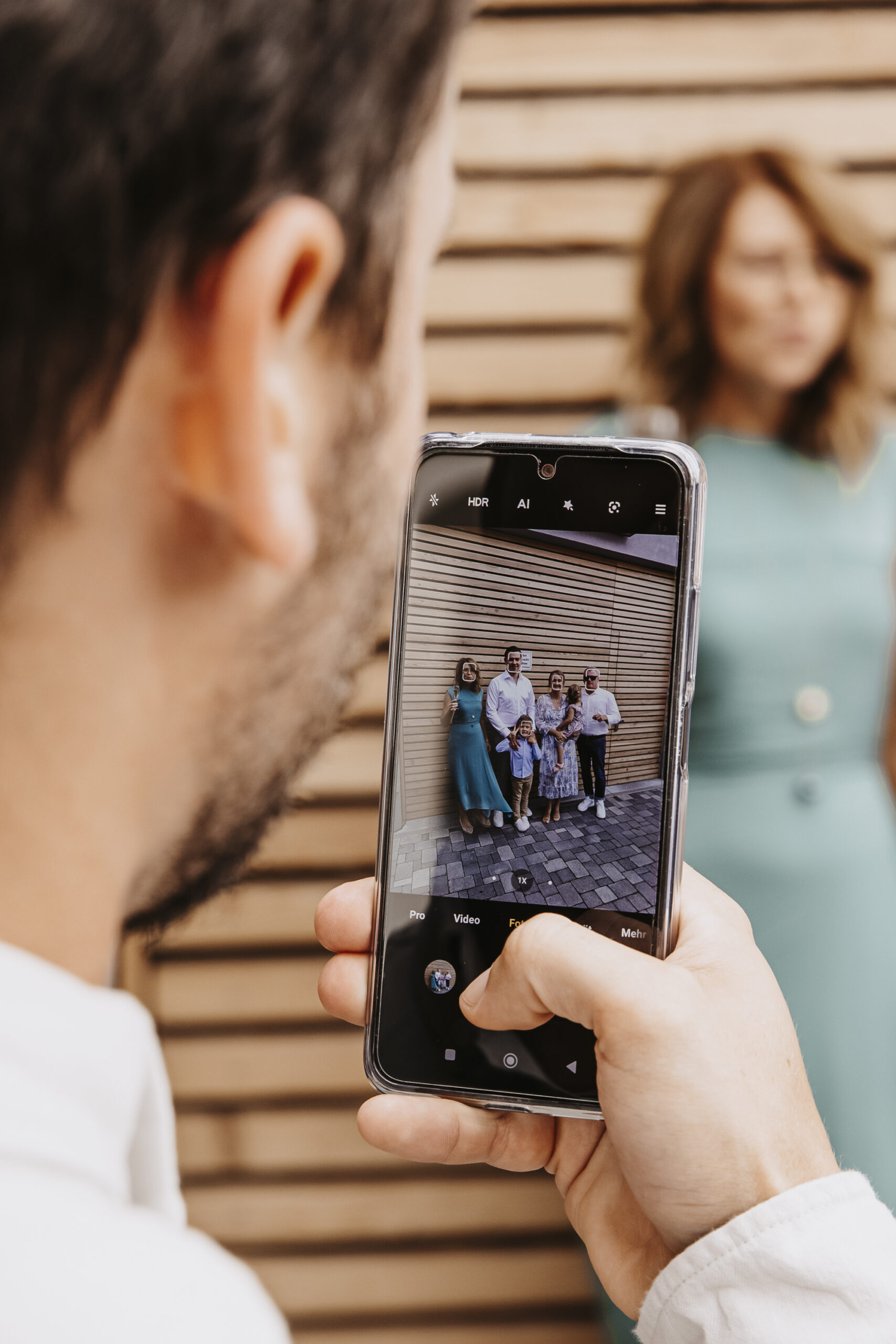 Kleiner Ausschnitt auf ein Handydisplay wie ein Hochzeitsgast die Hochzeitsfamilie fotografiert