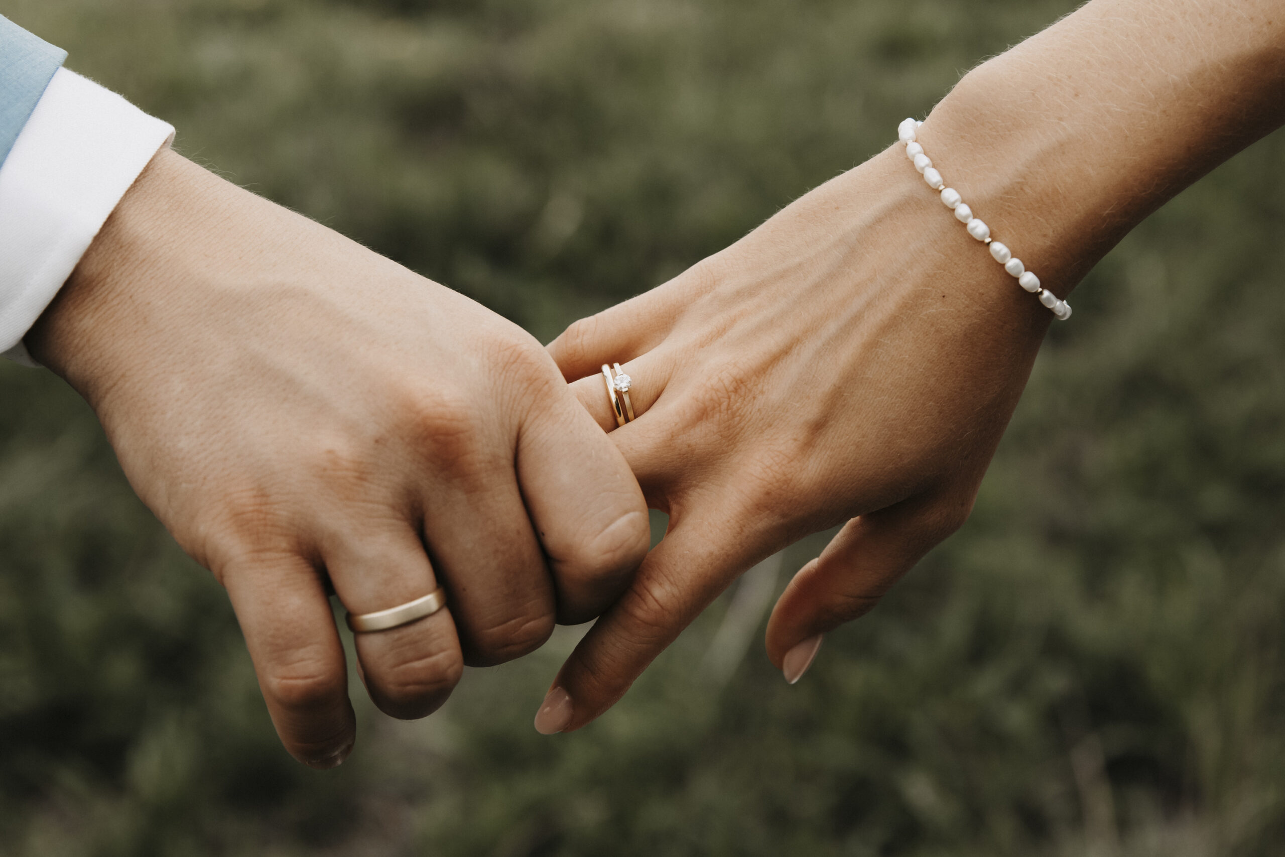 Nahaufnahme der Hände des Brautpaares, sie halten sich fest gegenseitig und zeigen damit ihr Zeichen der Verbundenheit