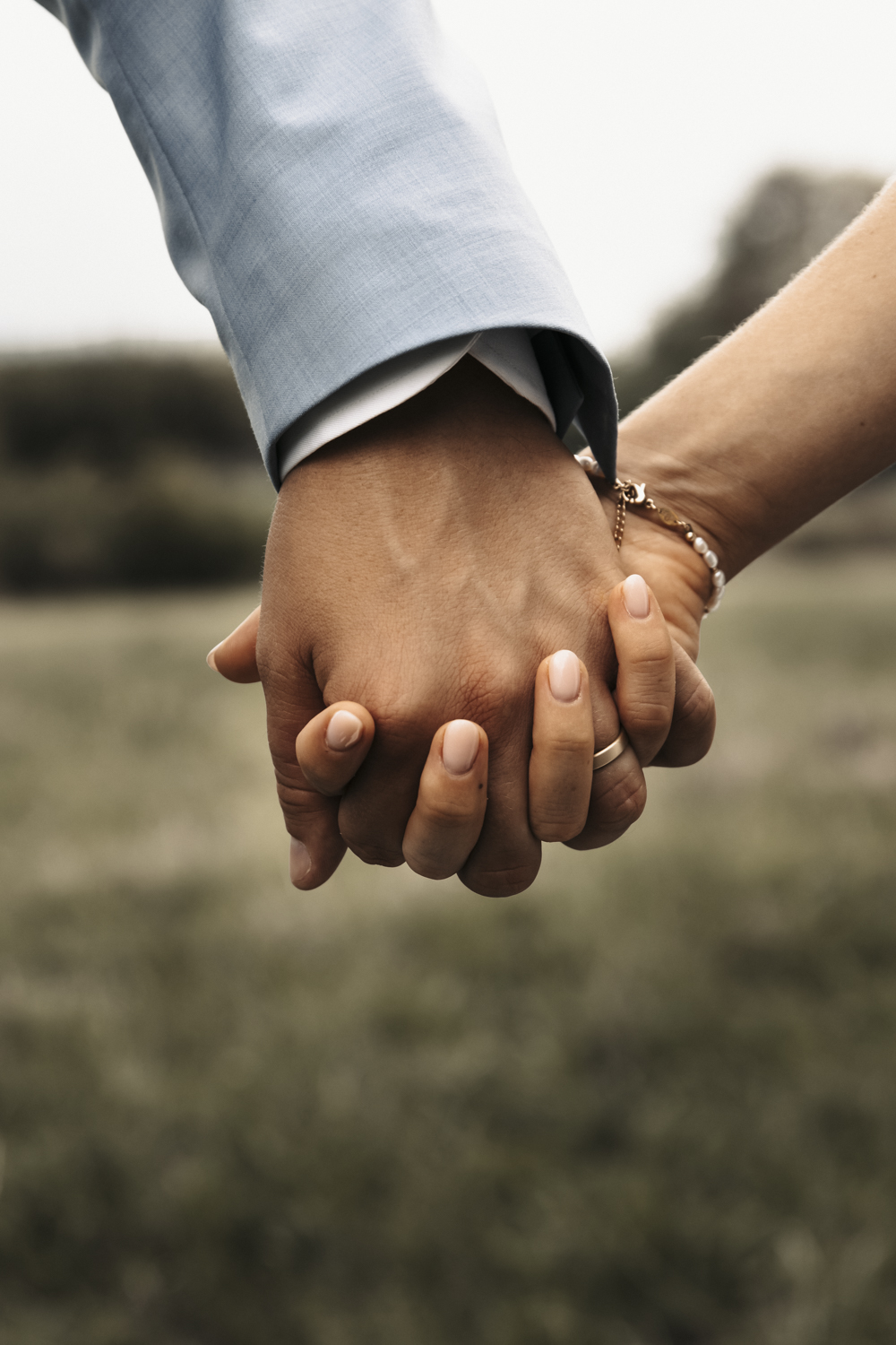Nahaufnahme der Hände des Brautpaares, sie halten sich fest gegenseitig und zeigen damit ihr Zeichen der Verbundenheit