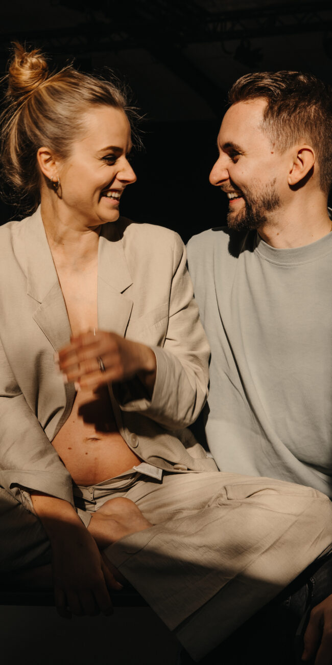Ein verliebtes Paar schaut sich lachend an während einem Maternityshooting & Coupleshooting in Zürich. - Hochzeitsbilder Schweiz