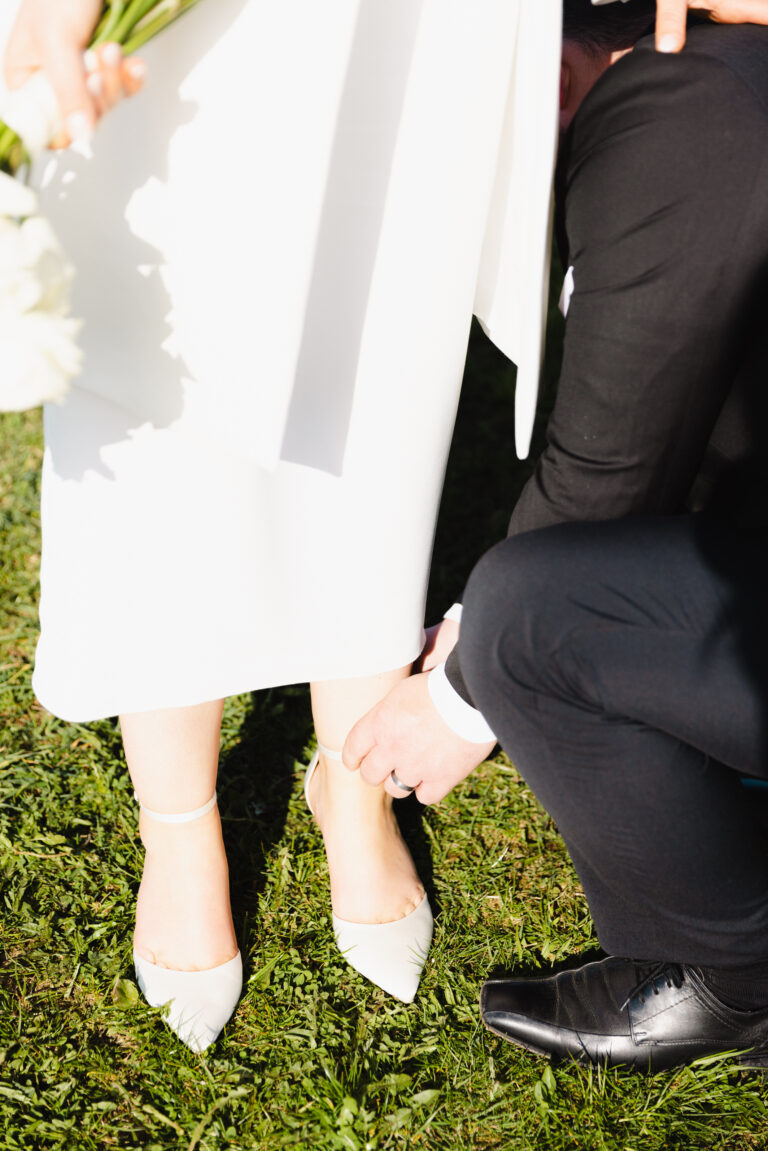 Der Bräutigam macht in einer Detailaufnahme seiner Braut die Schuhe zu. Bild in Farbe aufgenommen während eines Hochzeitsshootings im Schwarzwald