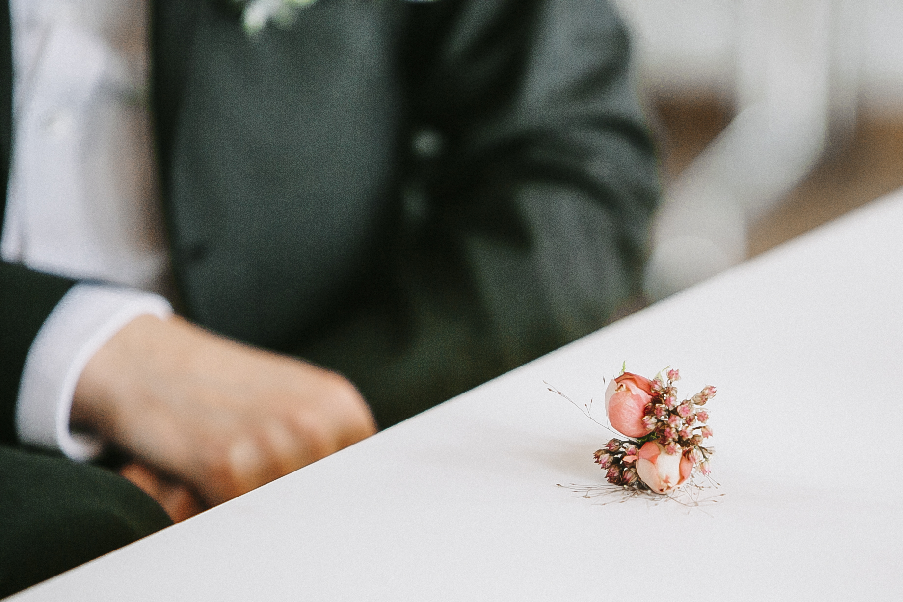 Detailaufnahme von einem sehr kleinen Blumengesteck was dem Bräutigam gehört um in den sakko einzustecken. Kleine Rosen in Rose.