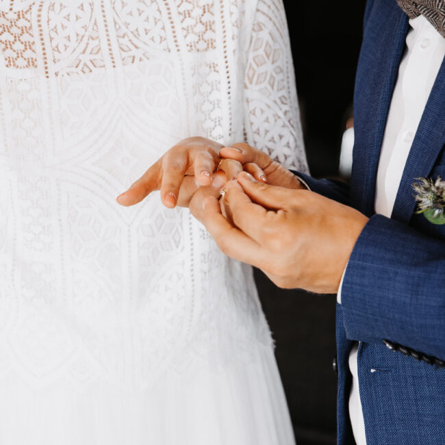 Detailaufnahme wir ein Mann seiner zukünftigen Frau den Hochzeitsring ansteckt während dem Standesamt und nach dem Ja-Wort
