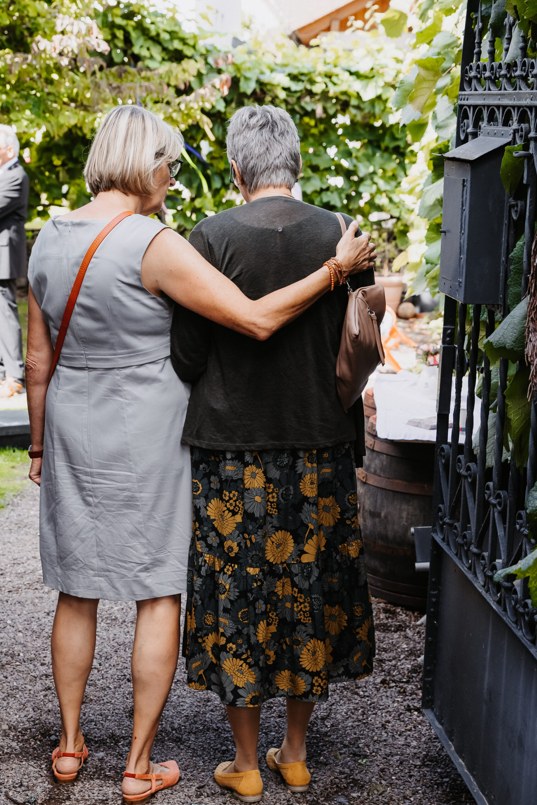 Brautmutter und ihre Schwester umarmen sich. Bild von hinten aufgenommen im Hinterhof des Sektempfangs.