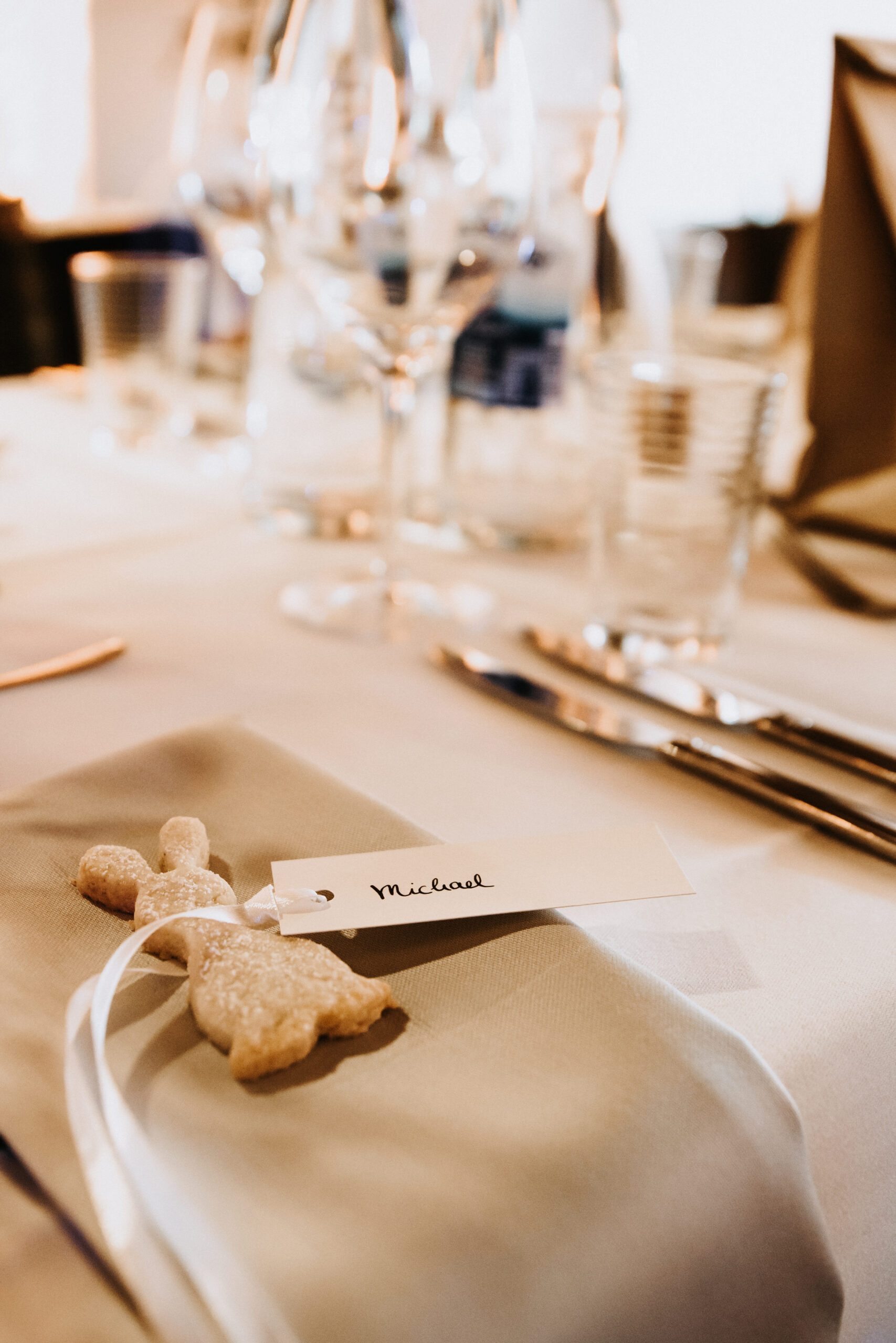 Detailaufnahme der Hochzeitsdekoration und Tischnamenkärtchen. Mit einem weißen Band an einem Kekshasen fest gemacht.