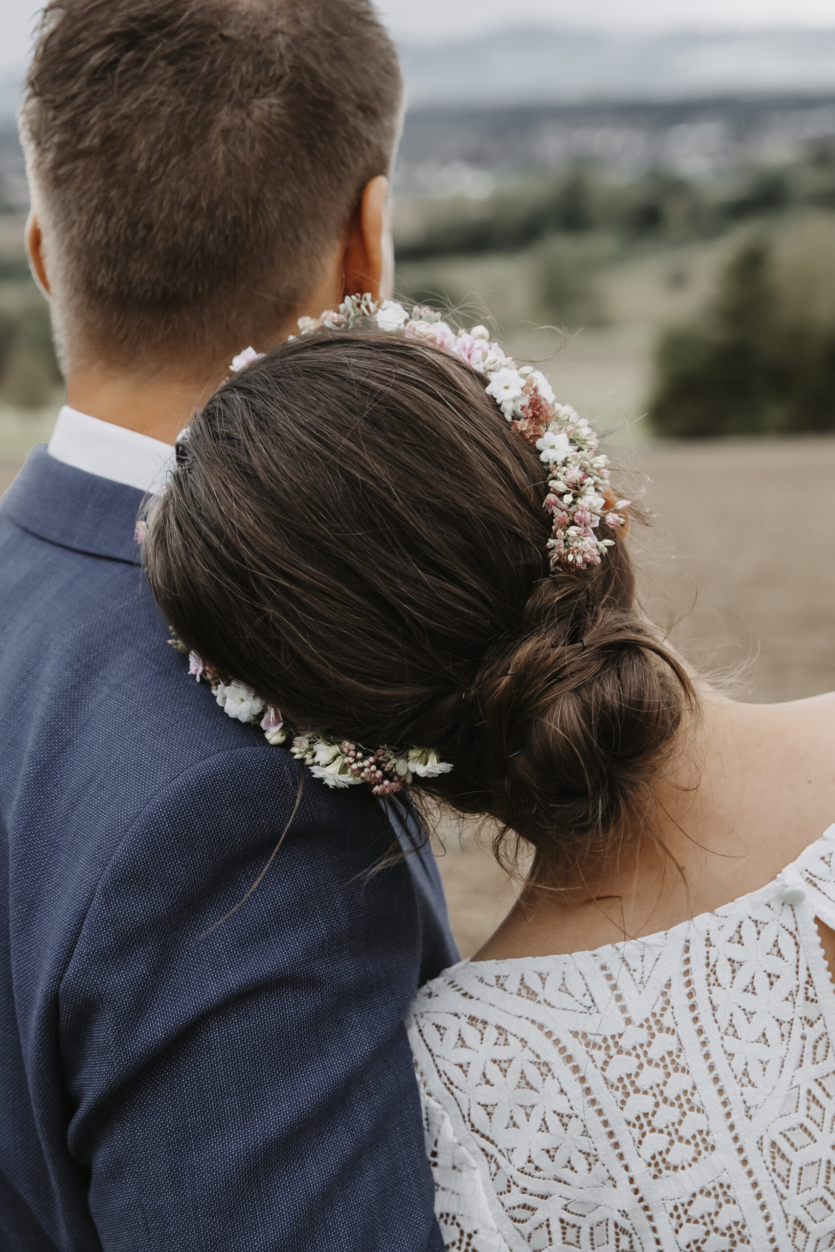 Brautpaarshooting - Ehemann und Ehefrau - Coupleshoot - weddingshooting - Bridedress - Köpfe von hinten im Hochzeitsoutfit mit Haarblumenkranz bei der Frau.