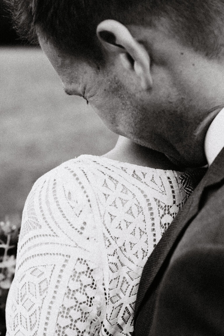 Bräutigam küsst die Braut von hinten auf die Schulter und in den Nacken. Aufgenommen von einer Hochzeitsfotografin aus Zürich.