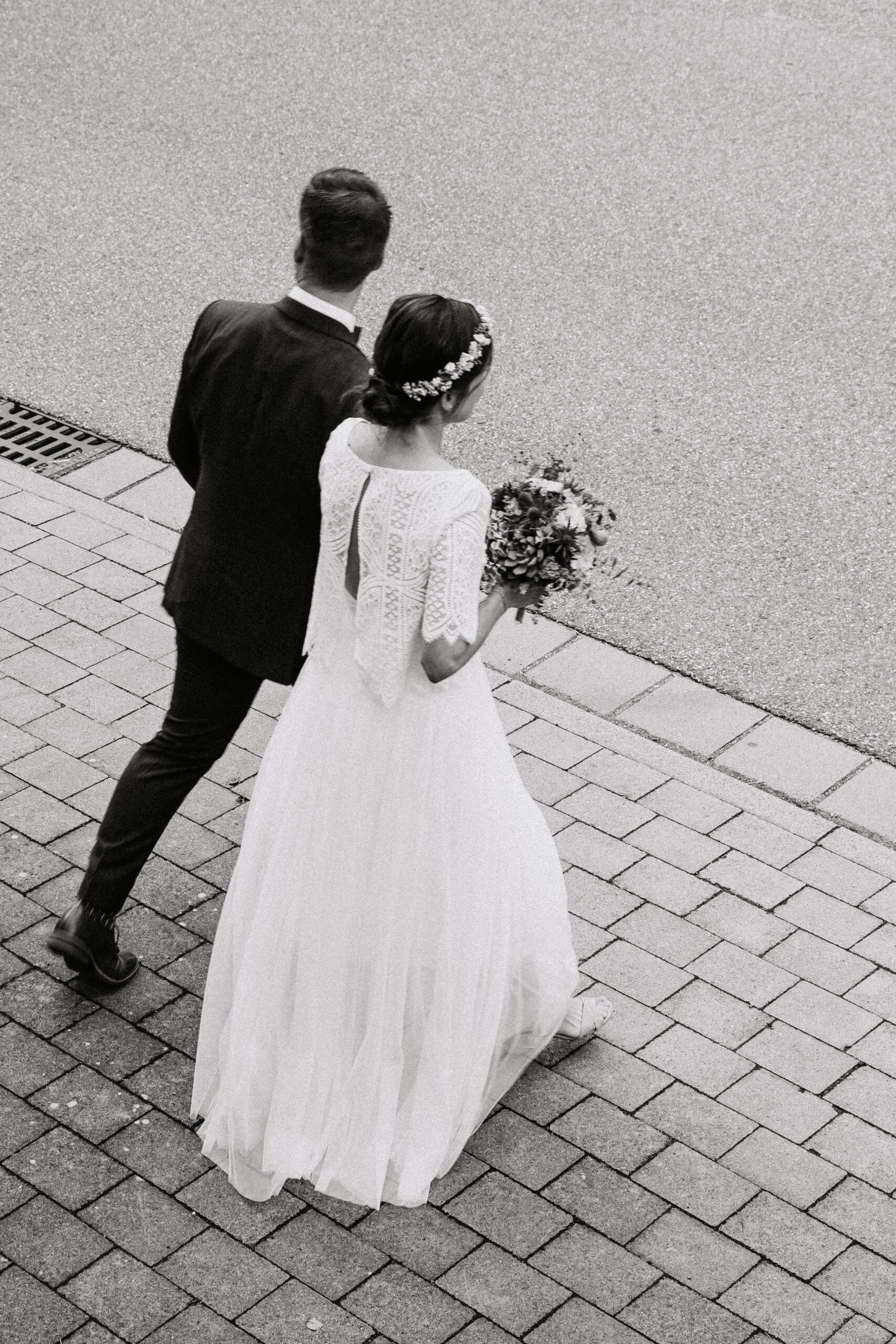 Schwarz weiß Aufnahme vom Brautpaar welches nach der Standesamtlichen Hochzeit händchenhaltend zum Auto läuft