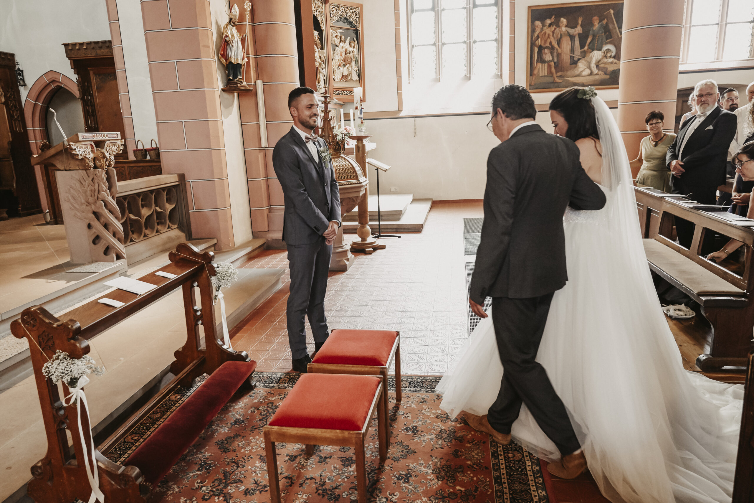 Der Brautvater begleitet die Braut zum Altar wo der Bräutigam auf die beiden wartet. ein sehr emotionaler Moment in der Kirche und der kirchlichen Trauung in Freiburg