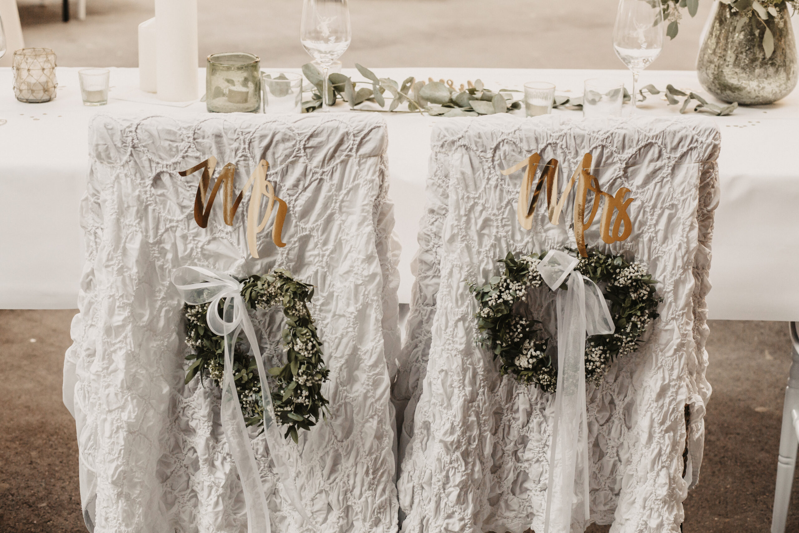 Die dekorierten Brautpaarstühle mit Mr. and Mrs. Aufschrift in Gold auf Weiß für das Abendessen in der neuen Location im Unteribental