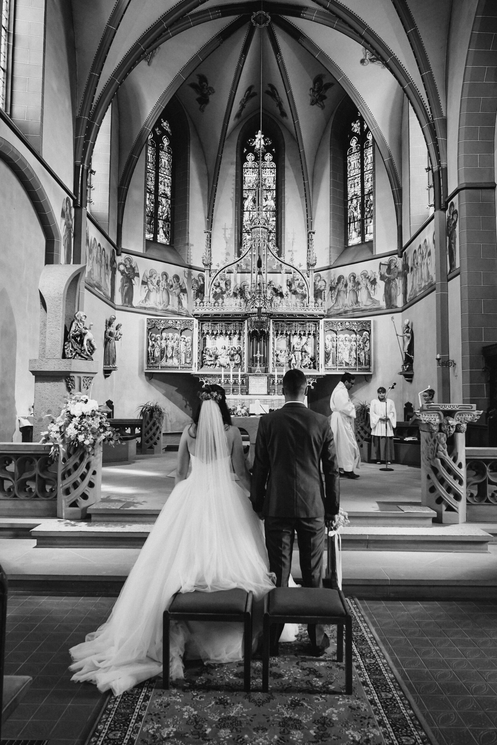 Das Brautpaar in der Kirche bei der kirchlichen Trauung in Zürich am Händchen halten und Küssen während der Eheschließung