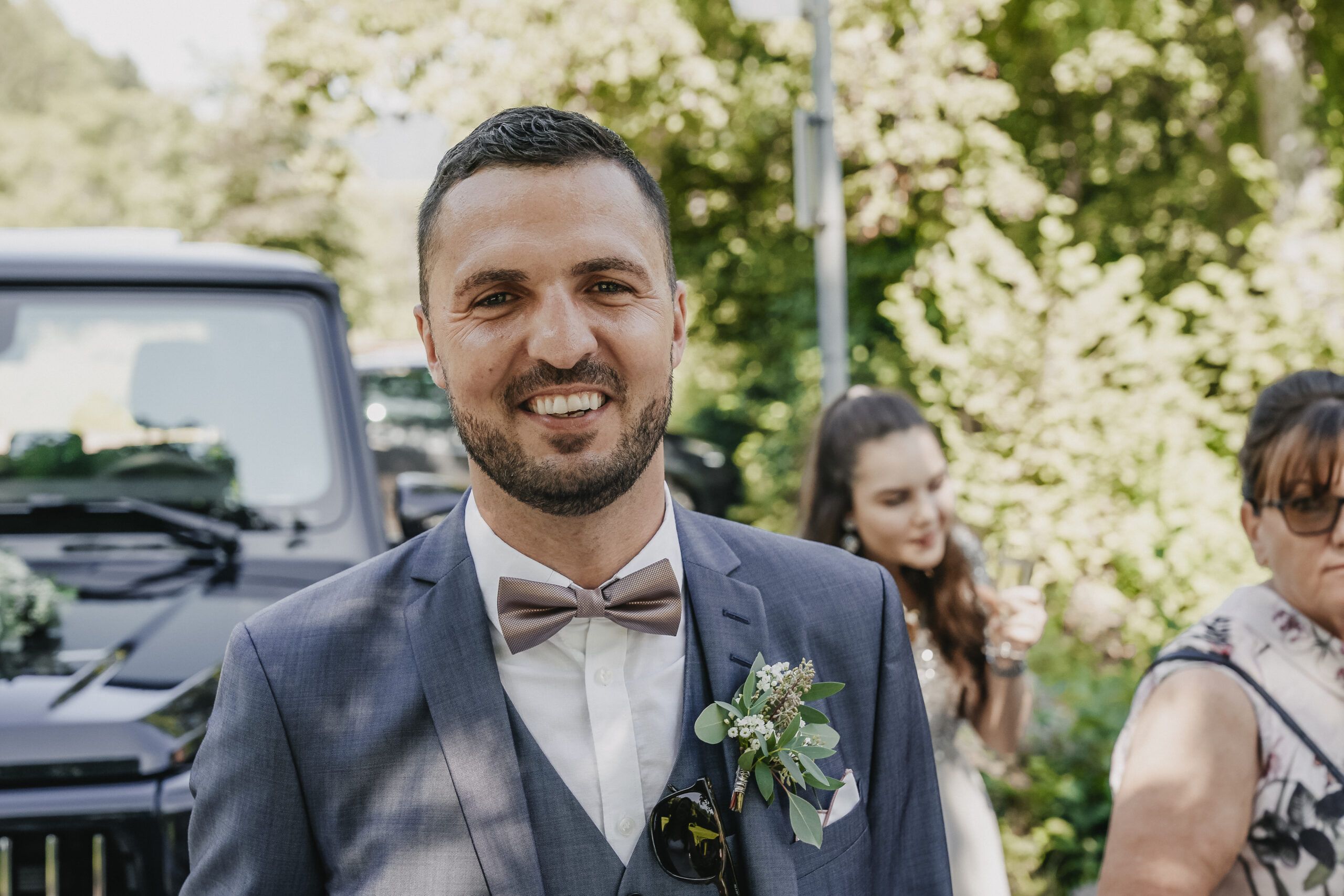 Der Bräutigam schaut glücklich in die Kamera. Portraitaufnahme während dem Sektempfang nach der Standesamtlichen Trauung.