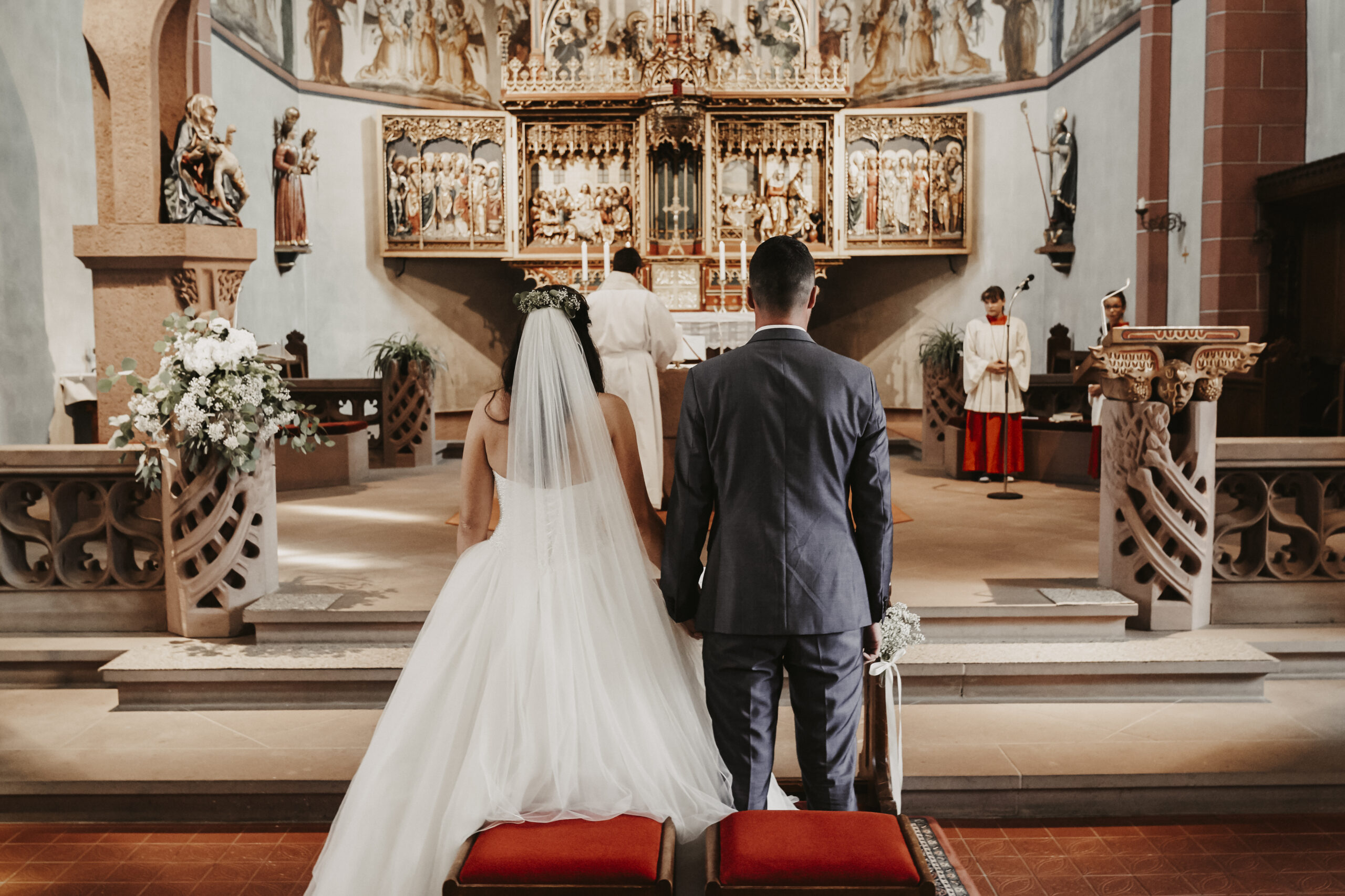 Das Brautpaar in der Kirche bei der kirchlichen Trauung in Zürich am Händchen halten und Küssen während der Eheschließung