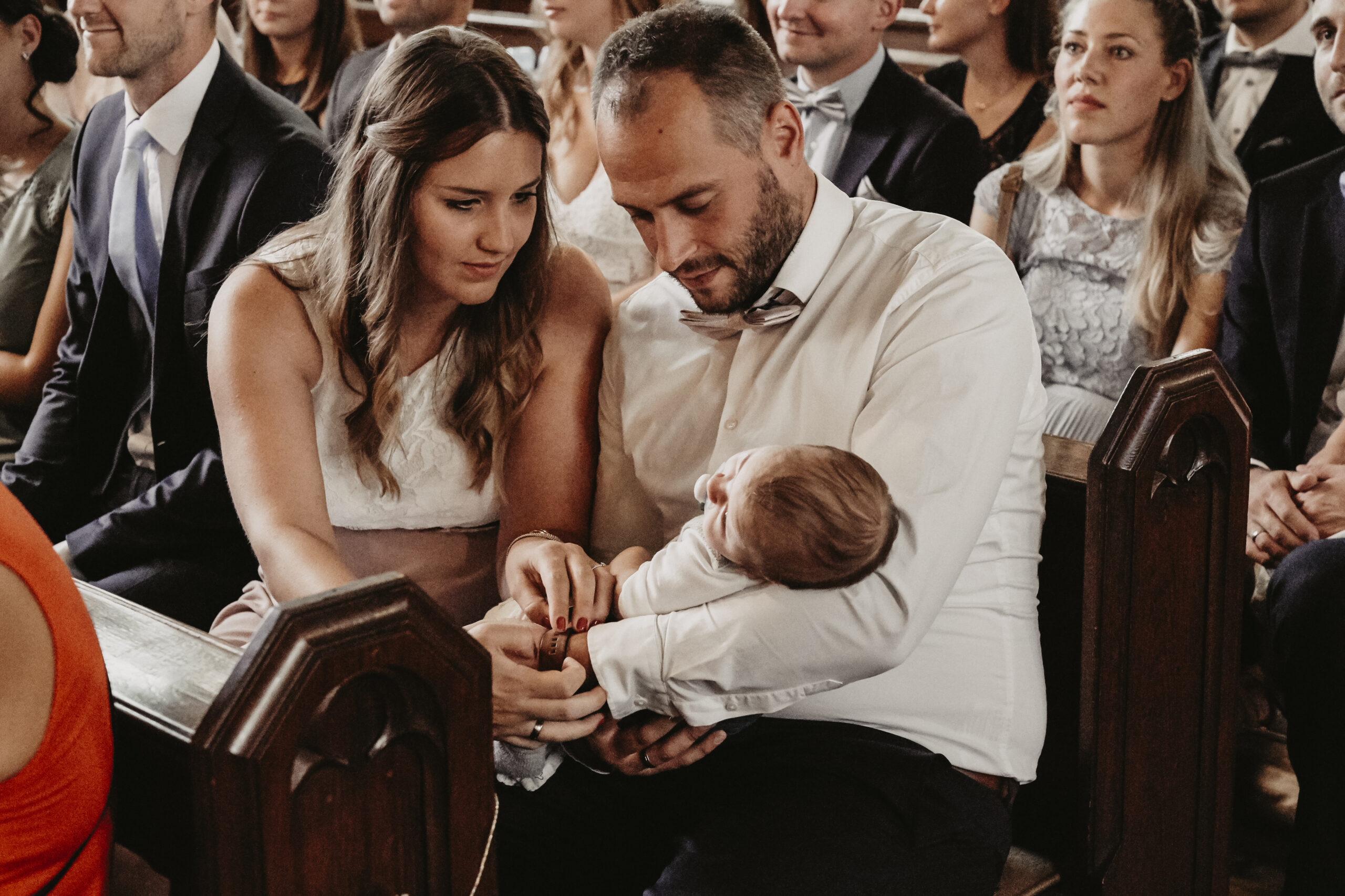 Eine kleine Familie hat ihre Aufmerksamkeit auf ihrem Baby und der Mann hat das Baby im Arm während der kirchlichen Trauung