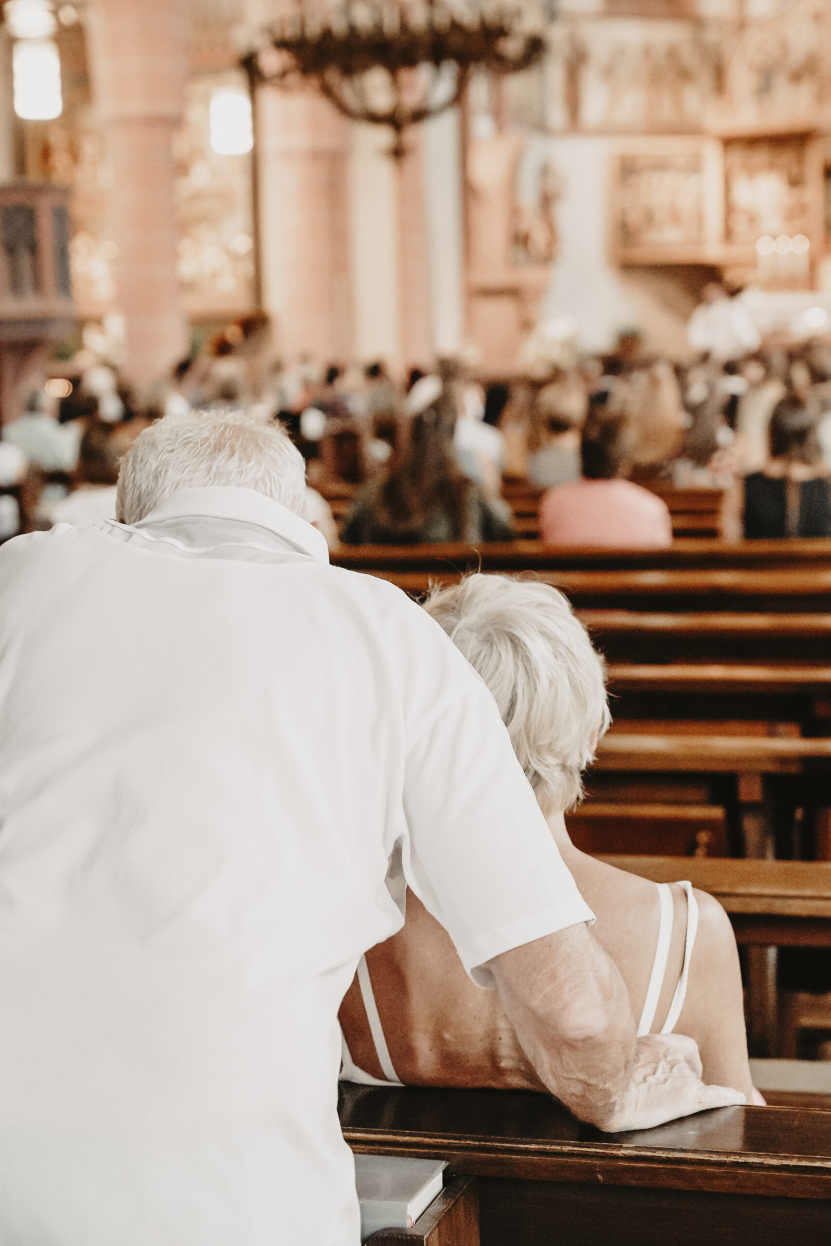 ein älteres Ehepaar von hinten wie sie gespannt der kirchlichen Hochzeit zu schauen