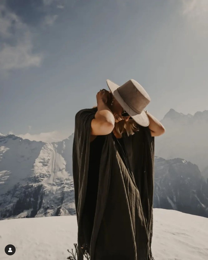 The Weddingphotographer in the Swiss Alps during a photoshoot wearing a hat and a ponjo from Mexico