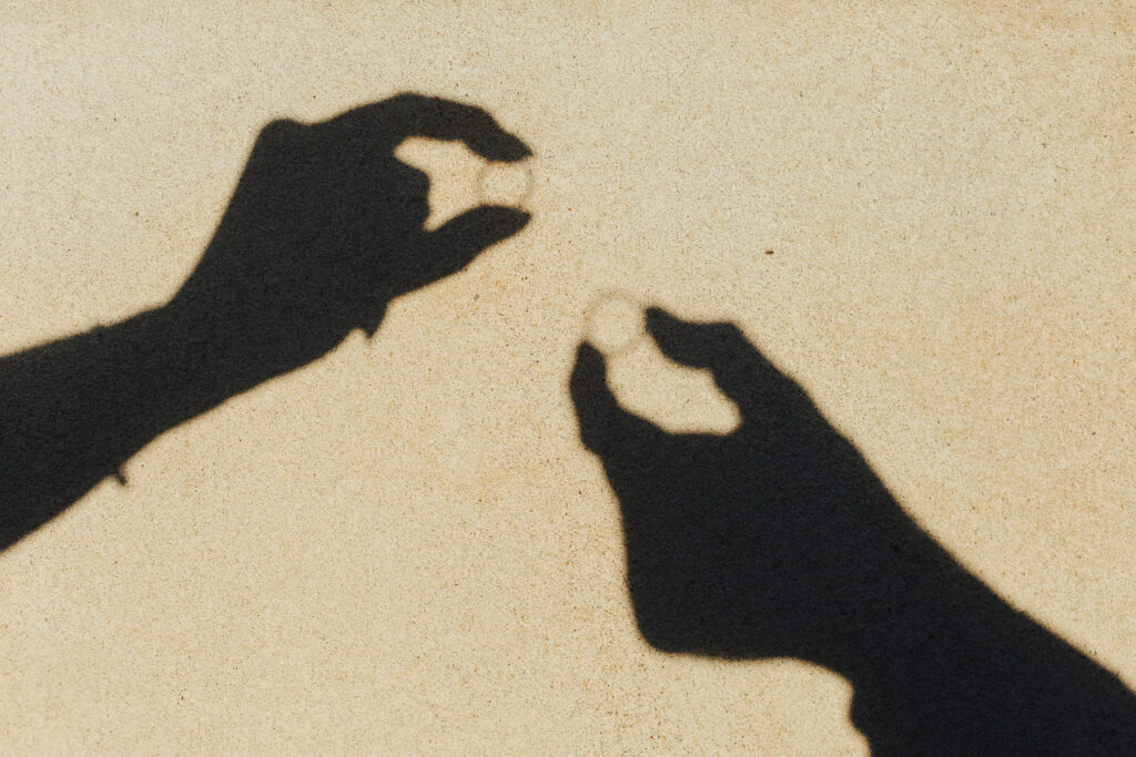 Standesamt - Brautpaar läuft Arm in Arm über die Wege der Altstadt und in der Nähe vom Münsterhof in Zürich nach ihrer standesamtlichen Trauung in Küsnacht. Auf dem Bild sind nur die Eheringe und die Hände des Brautpaares im Schatten zu sehen.