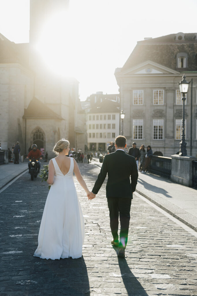Brautpaar läuft Arm in Arm über die Wege der Altstadt und in der Nähe vom Münsterhof in Zürich nach ihrer standesamtlichen Trauung in Küsnacht.